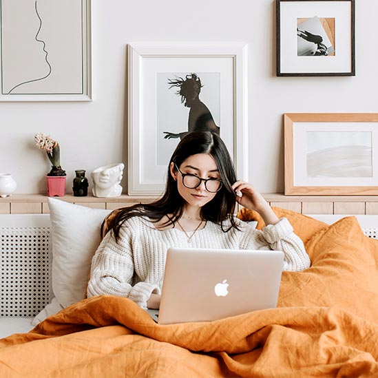 Woman Working on Laptop in Bed